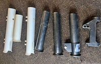 All seven rod holder components laid out, three white, three black, one bracket