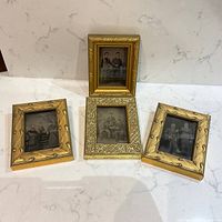 Four gilt-framed tintype photographs displayed on countertop