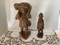 Front view of both wood figurines on lace cloth