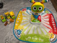 Play mat, electronic topper, three toy trucks and five blocks displayed on floor