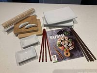 Full set laid out: plates, sauce dishes, chopsticks, bamboo tools, booklet