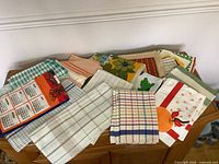 Group of assorted tea towels spread on tabletop showing variety of patterns