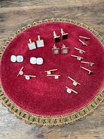 Full view of all cufflinks and studs on red velvet pad