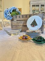 Front view of stacked plates, glass bowl, gold leaf dish, green tree dishes