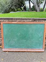 Front view of full chalkboard showing green surface, wood frame and chalk tray