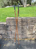 Full view of both wooden ski poles leaning against wall