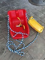 Red infant swing seat overview with rope and front bar visible