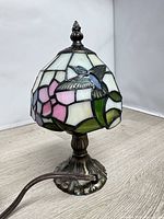 Front view of stained glass lamp showing bird and floral design, full base visible