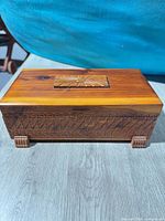 Front view of carved wooden jewelry box on four feet