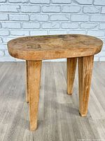 Front view of wooden stool showing oval seat and legs