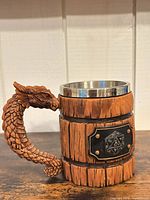 Front angle showing barrel texture, stainless rim, dragon handle, D20 plaque