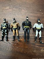 Front view of all four Batman figures on wooden surface