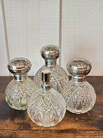 Front view of all four pressed glass perfume bottles showing pattern and caps