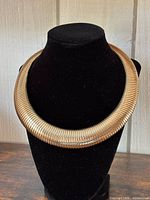 Front view of gold tone tubogas collar necklace on black bust
