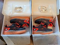 Two open boxes each containing a pair of LED sneakers with USB charging cable