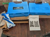 Closed blue hard cases, gloves and user manual visible