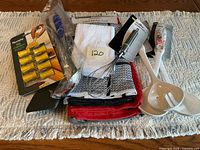 All items grouped on table: corn holders, tongs, whisk, two spoons, stack of towels