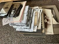 Stack of various vintage photographs and cabinet cards on countertop
