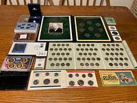 Overview of all coin sets, folder, pin and Desert Shield cover spread on table
