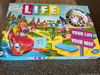 Front of unopened Game of Life box showing artwork, spinner and car illustration