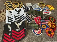 Overall view of assorted rank chevrons and company/novelty patches spread on surface