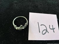 Sterling silver ring shown on dark background beside lot number card