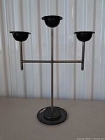 Full view of brushed silver metal candelabra with three black candle cups