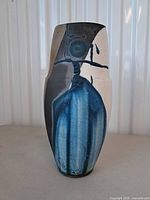 Front view of raku vase showing blue drip glaze over white body