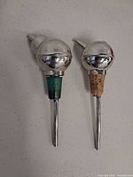 Front view of both silver-plated pourer spouts showing stoppers and dip tubes