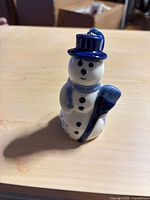 Front view of ceramic snowman ornament showing blue details and broom