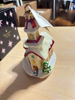 Front view of glass church ornament with tag attached, box in background