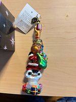 Full view of ornament showing snowman head, present, sack and bauble, with tags attached