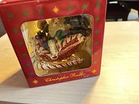 Front view of boxed Christopher Radko Santa sleigh glass ornament through window