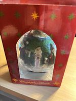Front view of ornament in original red Christopher Radko box