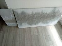 Large and small abstract glitter canvases leaning against wall on floor