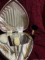 Open heart case showing all grooming items inside and shaving brush outside