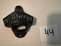 front view of cast iron bottle opener showing "OPEN HERE" text and mounting holes