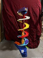 Full view of assembled multicolor plastic spiral car ramp tower on blue base