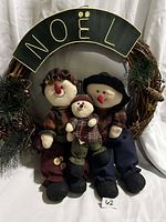 Front view of wreath showing Noel plaque, three snowmen, greenery, pinecones and berries