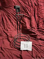 Full view of black metal hair dryer holder showing over-door hook and circular base