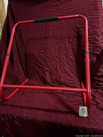 full view of red metal skate assist frame on maroon backdrop