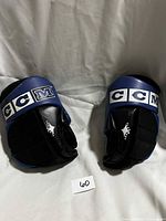 Front view of both CCM youth hockey gloves showing blue/black colour and CCM cuff logos