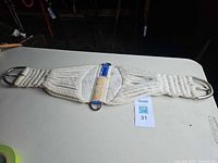 Full view of braided cotton horse girth showing length, center O-ring, leather and nylon webbing accents