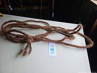 Full view of coir lead rope coiled on surface with leather handle visible