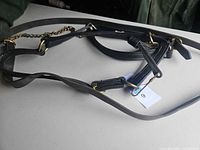 Full view of black leather reins with brass hardware and chain