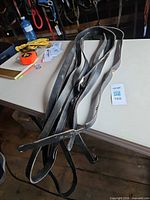 Full view of coiled black leather reins on table