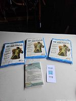 Four packaged ponchos on table; three SI brand and one Ozark Trail