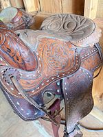 Side view of saddle showing floral tooling, latigo and stirrup