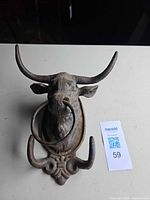 Front view of cast iron bull head wall hook showing horns, nose ring, lower hooks