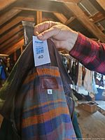 Hand holding coat collar with auction tag visible